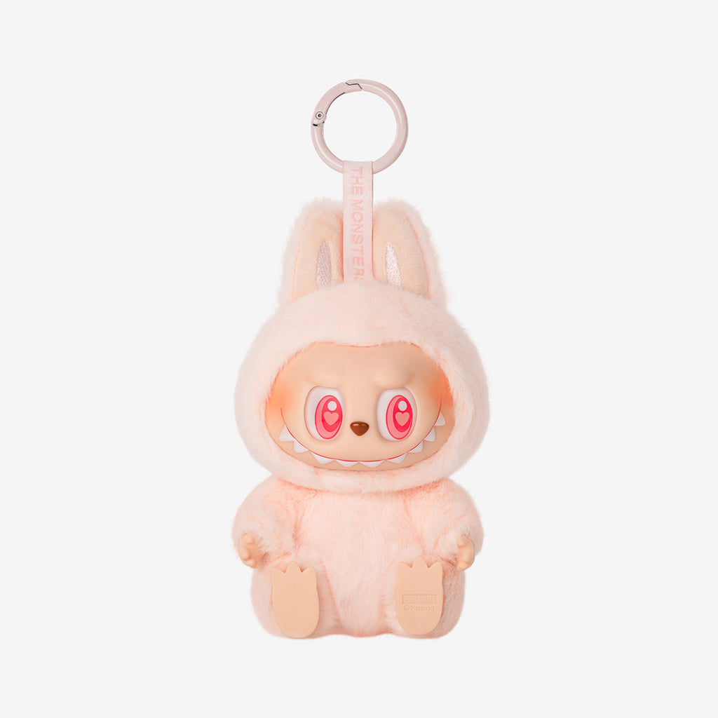 Labubu Dada keychain plush from the "Have a Seat" series, featuring a soft peach furry costume with bunny ears and wide-eyed smile, sitting with legs stretched forward.