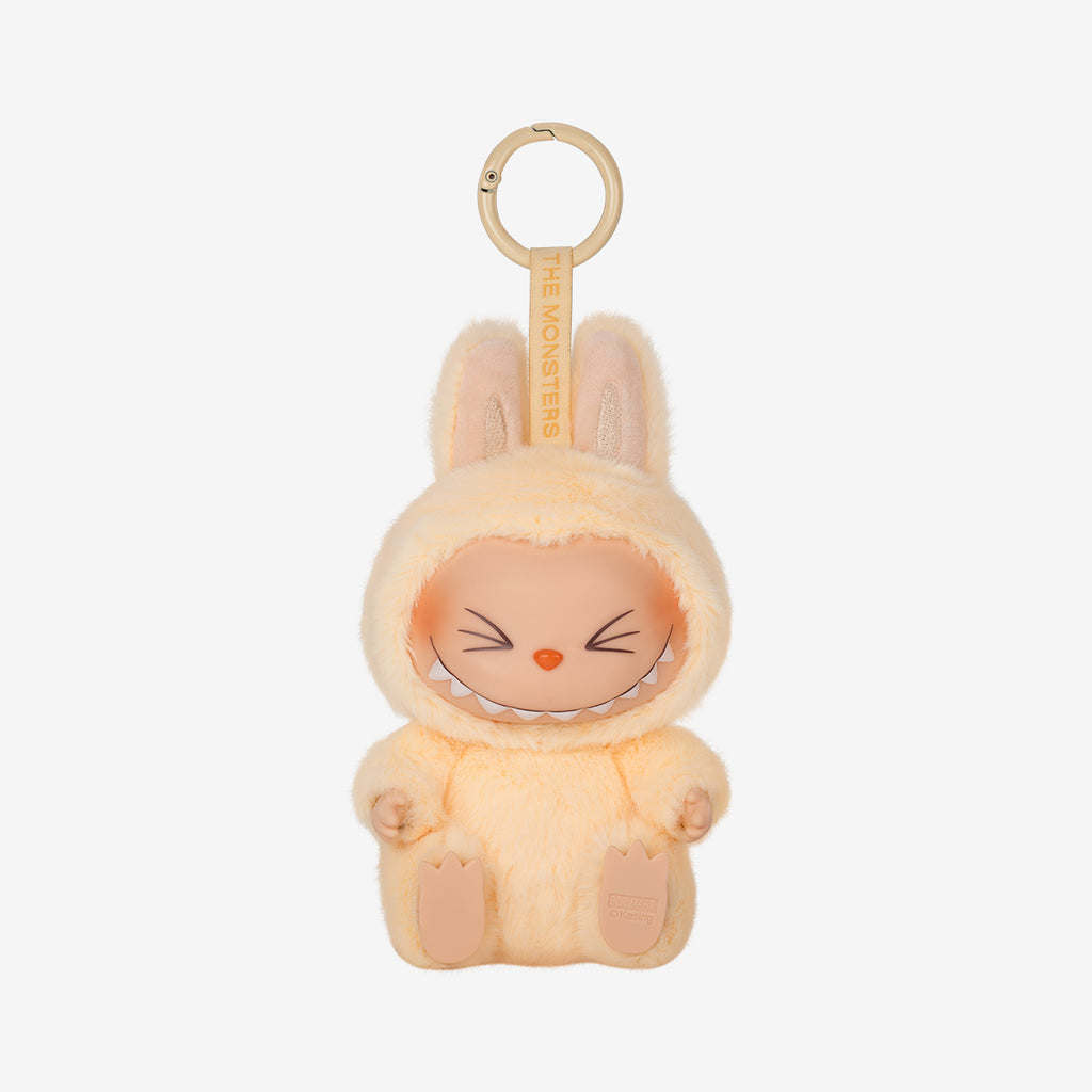 Labubu Sis keychain plush from the "Have a Seat" series, featuring a soft peach furry costume with bunny ears and wide-eyed smile, sitting with legs stretched forward.